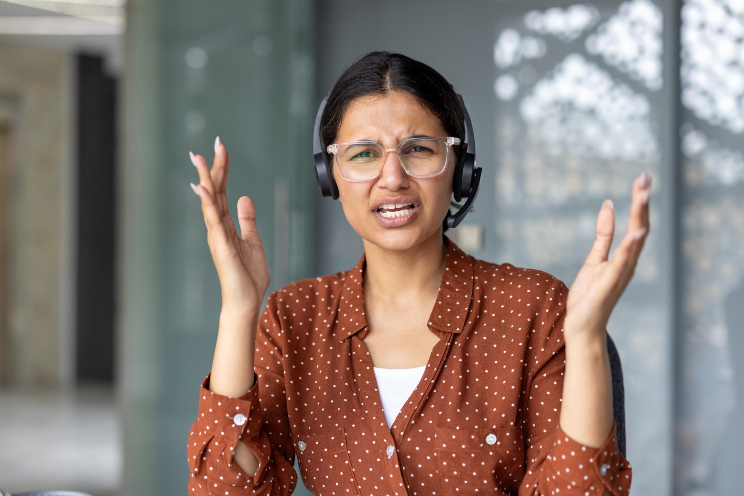 Customer support agent wearing a headset showing frustration while handling a difficult communication issue in an office setting