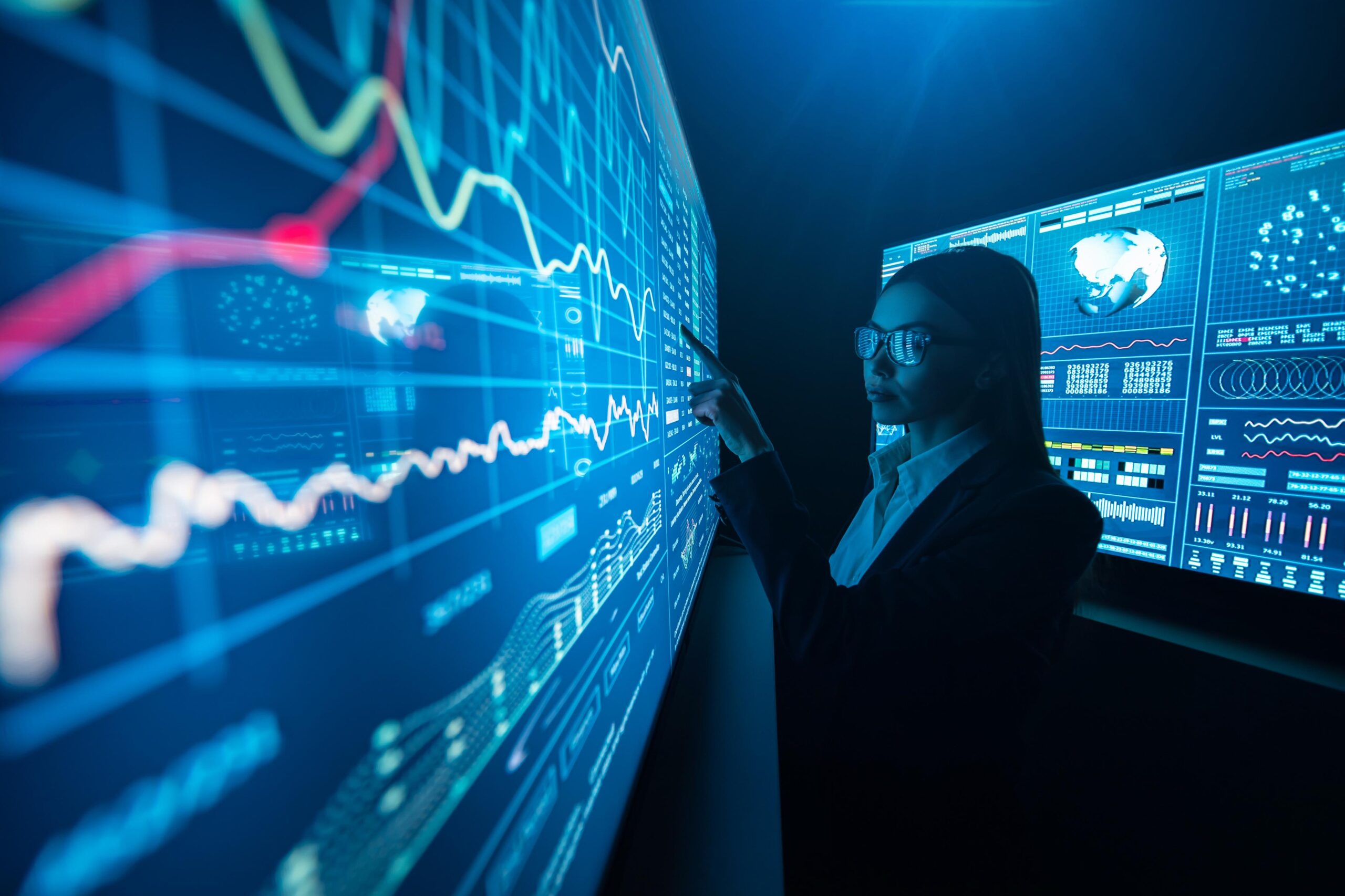 Professional analyzing large digital dashboards with data visualizations and performance metrics on interactive screens.